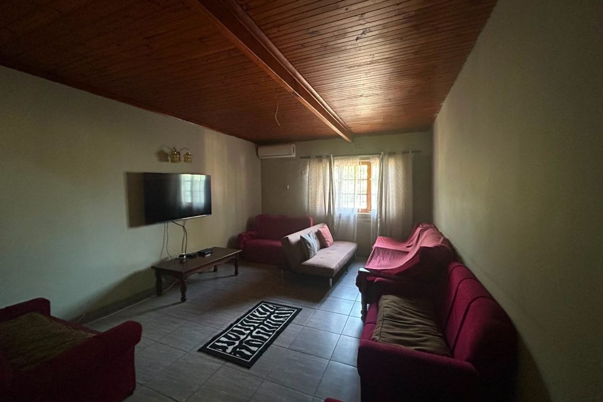 Living room featuring a vaulted timber-clad ceiling, tiled flooring, and a wall-mounted air conditioning unit.