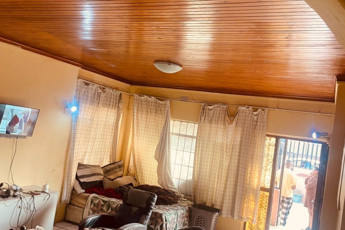 Living room featuring a timber tongue and groove ceiling, ceramic tiled flooring, and an arched entryway leading to the exterior.
