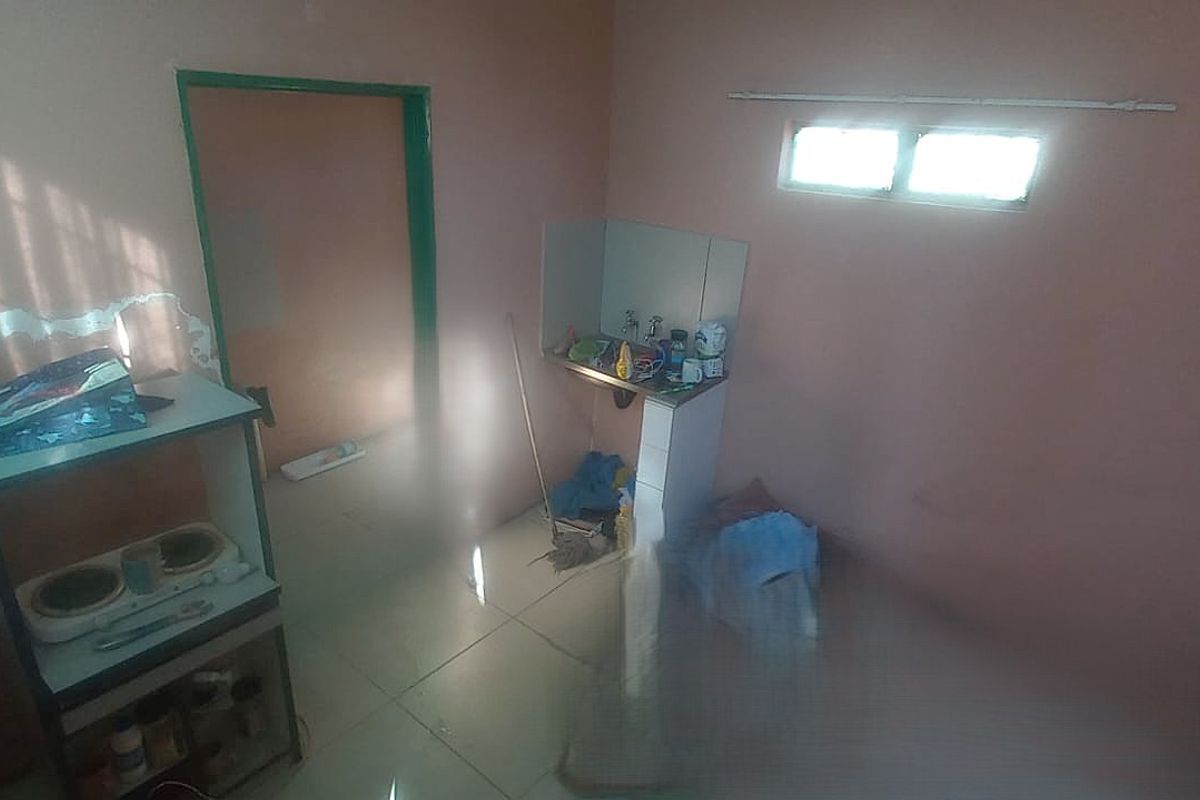 A small, basic kitchen area featuring tiled flooring and a simple sink unit, currently in need of cosmetic renovation and wall repairs.