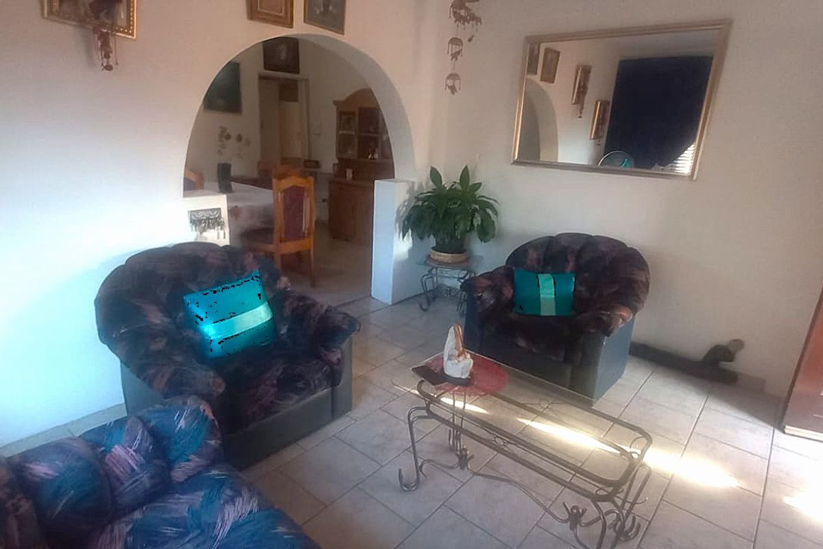 A living room area featuring tiled flooring and an arched doorway leading to an adjacent space, with a solid wood front entrance door.
