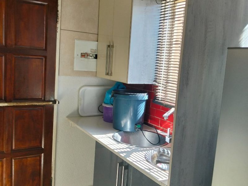 A functional scullery area featuring built-in cabinetry, a stainless steel sink, and tiled splashbacks, providing convenient additional prep and wash-up space.