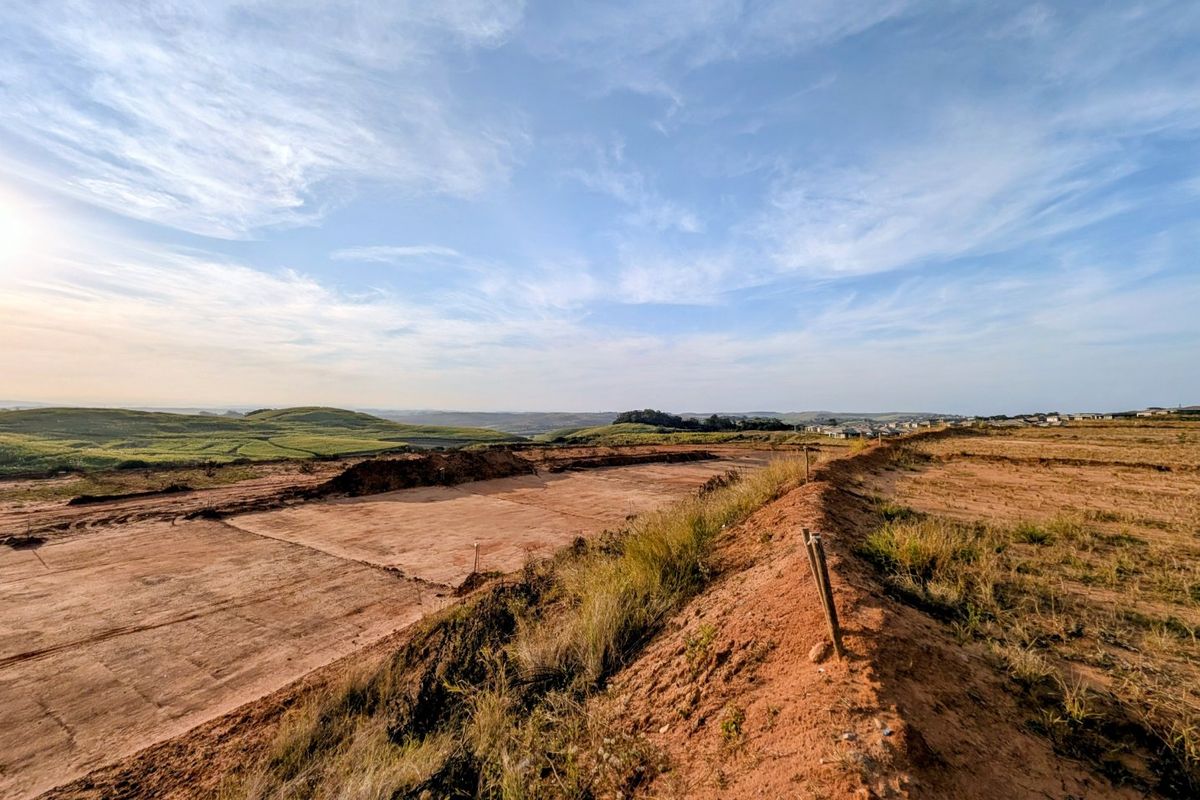 A wide-angle view of a cleared residential plot featuring leveled earthworks and expansive rolling landscape views.