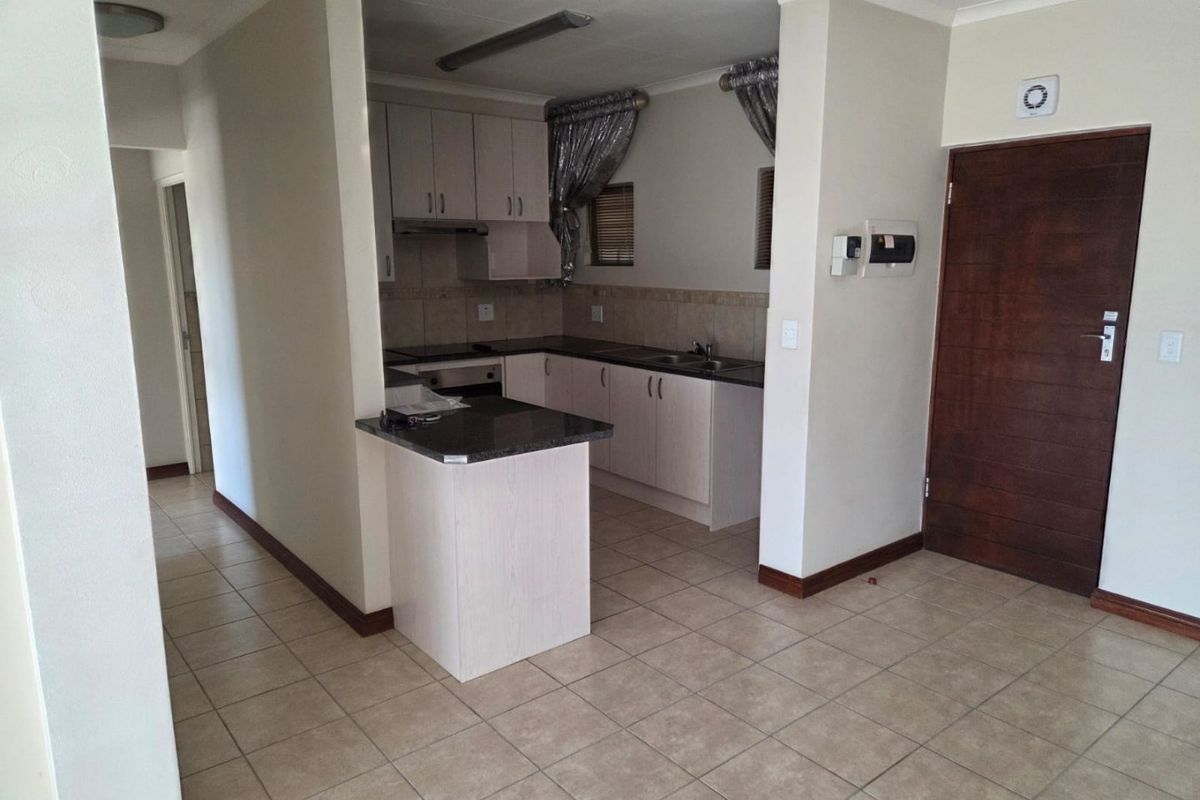 A functional kitchen featuring built-in cabinetry, granite countertops, a stainless steel sink, and tiled flooring, offering a clean and practical layout.