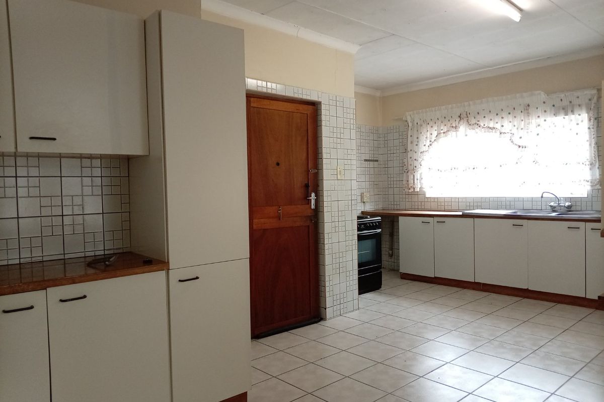 A functional kitchen featuring tiled flooring, white cabinetry, laminate countertops, and a tiled backsplash, offering a clean and practical layout.