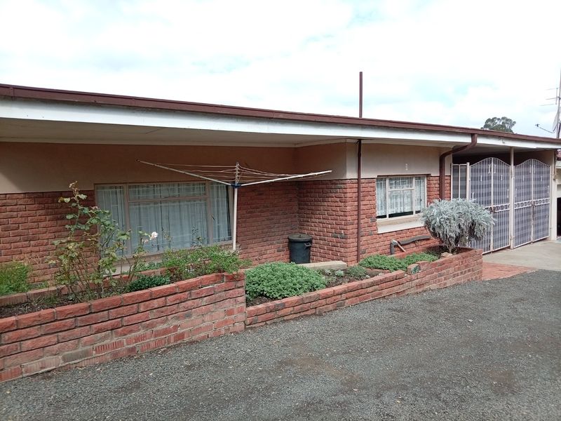 Front exterior view of the apartment building featuring a brick facade, covered veranda, and integrated brick planter boxes.