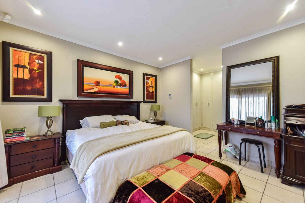 Spacious bedroom featuring tiled flooring, recessed downlighting, and integrated built-in cupboards, offering a clean and functional living space.