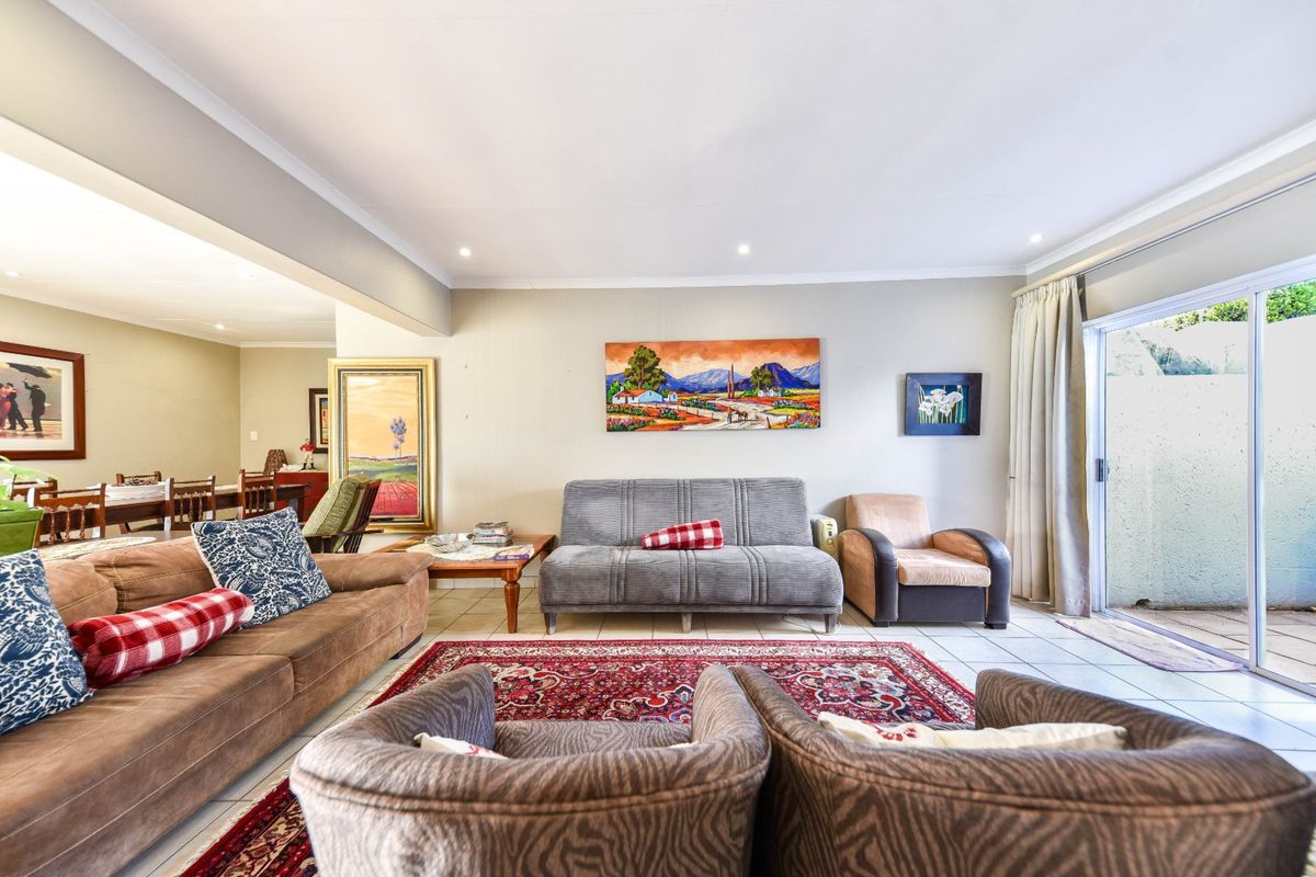 Spacious open-plan living area featuring tiled flooring, recessed lighting, and a large sliding glass door providing access to the outdoor patio.