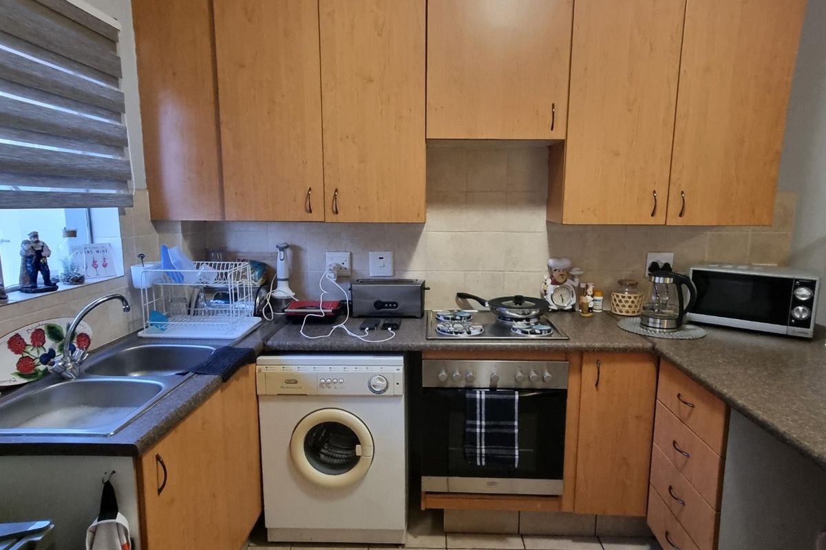 Functional kitchen featuring laminate cabinetry, built-in oven with gas hob, double bowl stainless steel sink, and tiled backsplash.