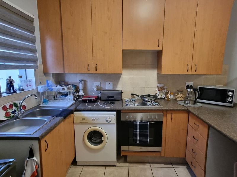Functional kitchen featuring laminate cabinetry, built-in oven with gas hob, double bowl stainless steel sink, and tiled backsplash.