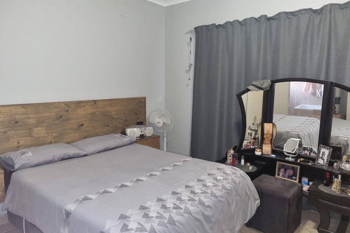 A bedroom featuring a built-in wooden headboard and tiled flooring, with direct access to an en-suite bathroom.