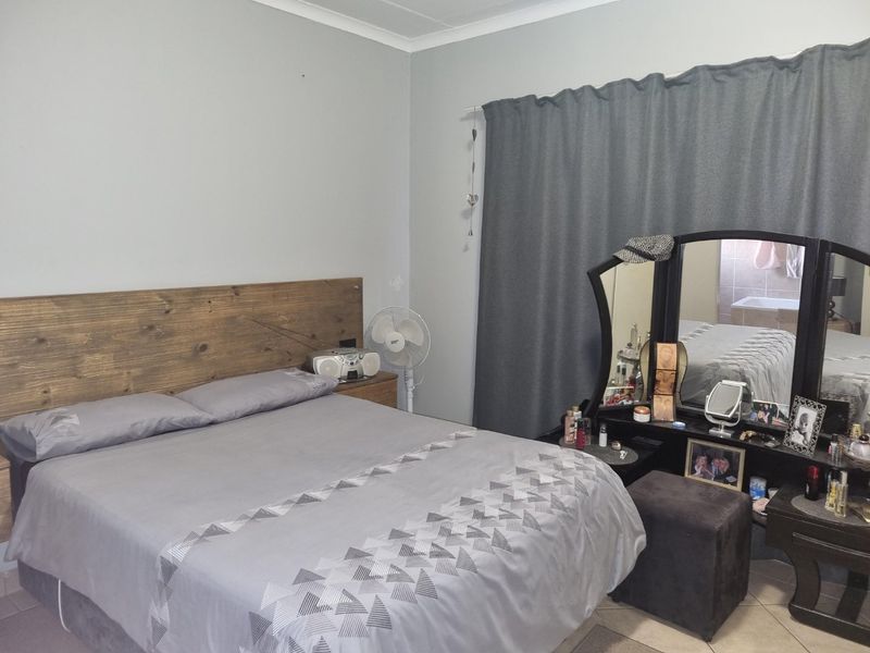 A bedroom featuring a built-in wooden headboard and tiled flooring, with direct access to an en-suite bathroom.