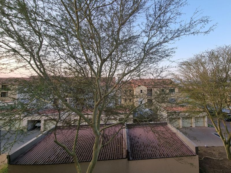 An elevated view overlooking the residential complex, featuring corrugated metal roofing and surrounding mature trees.
