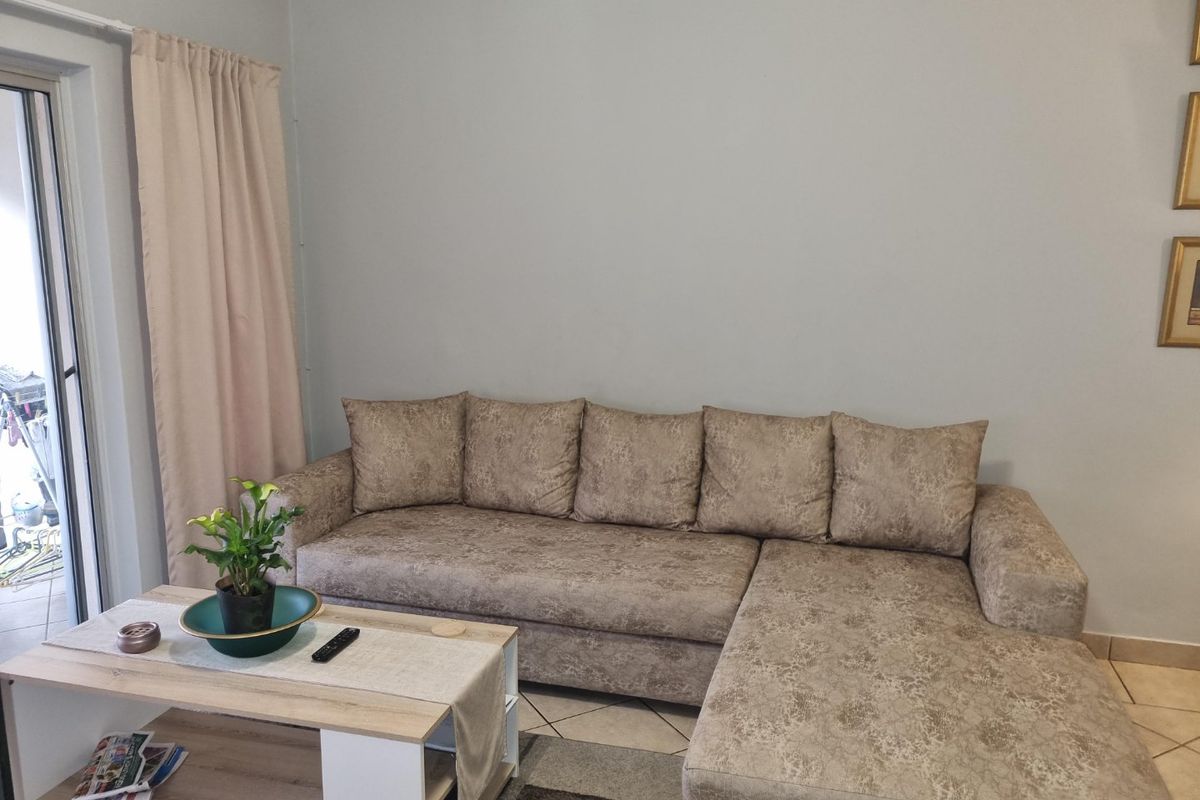 A living room area featuring tiled flooring and a sliding glass door providing access to the exterior.
