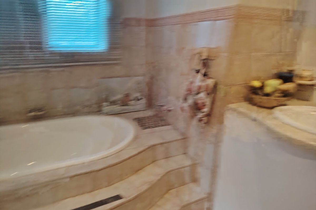 A dated bathroom featuring a built-in bathtub with tiled steps and a tiled vanity area, requiring modernization of finishes.