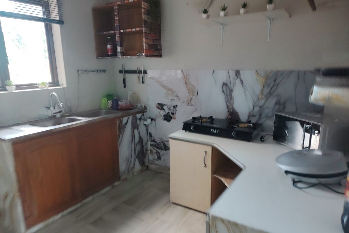 A functional kitchen featuring marble-effect splashbacks, wooden cabinetry, and a gas cooktop, offering potential for cosmetic updates to modernize the space.