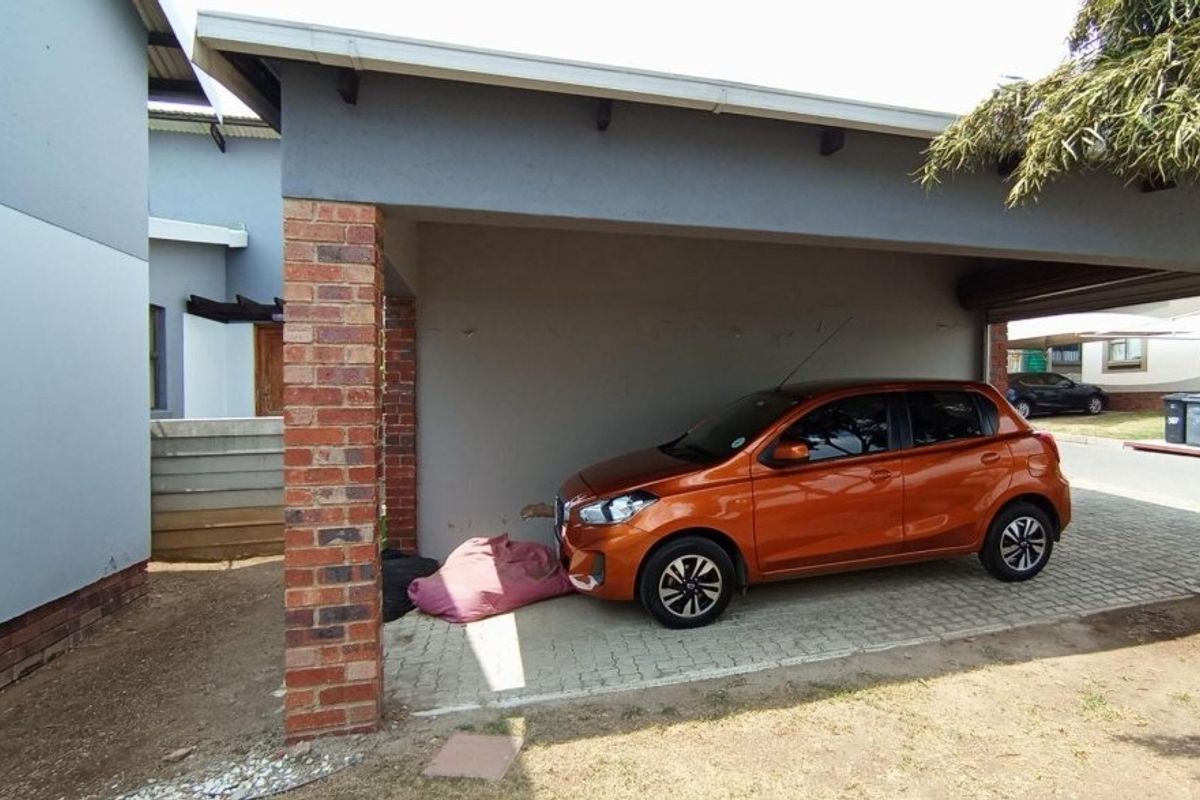 A covered carport area featuring a brick pillar support and paved flooring, providing sheltered parking space for the townhouse.