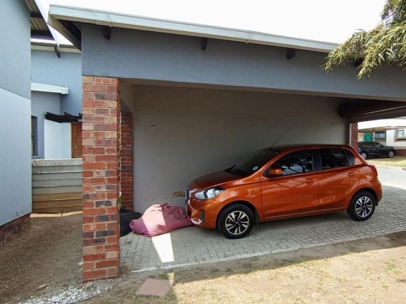 A covered carport area featuring a brick pillar support and paved flooring, providing sheltered parking space for the townhouse.