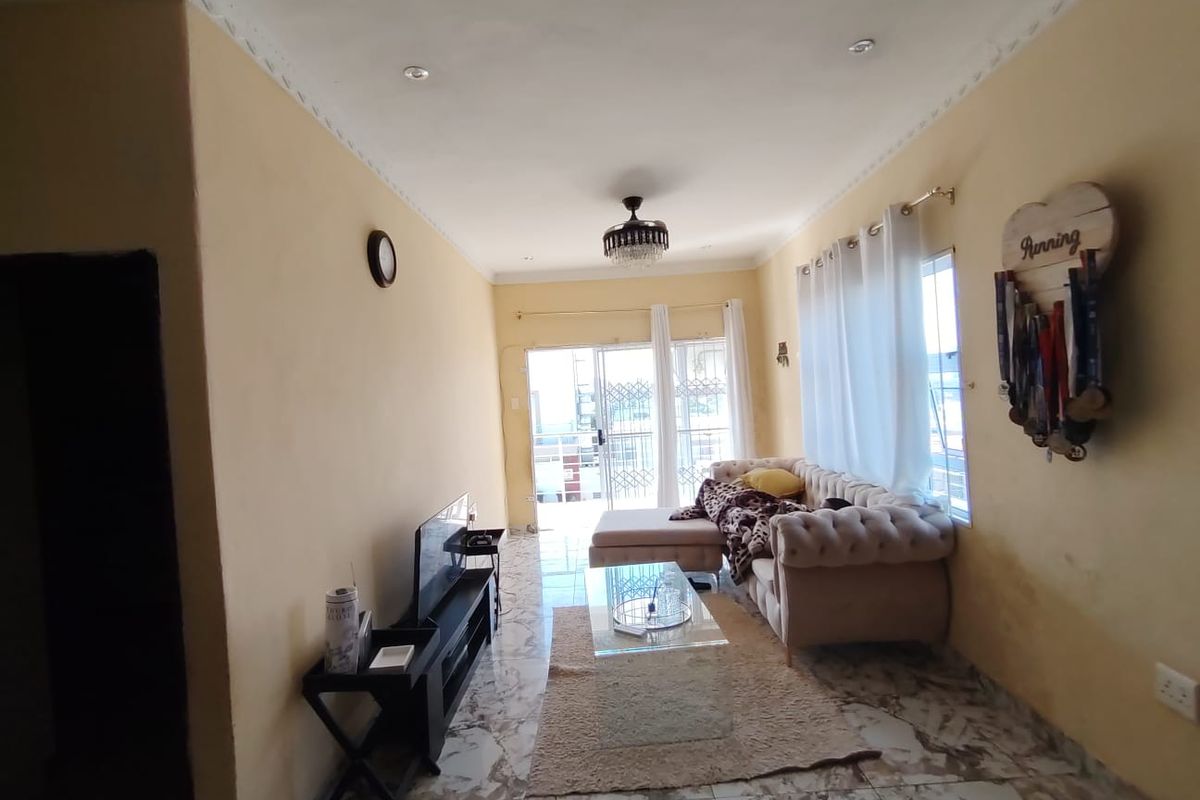 A living room featuring tiled flooring, recessed lighting, and a sliding glass door leading to an outdoor area.