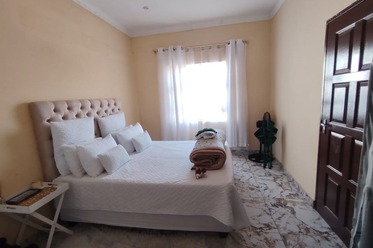 A bedroom featuring tiled flooring, recessed ceiling lighting, and a panelled door, providing a functional space with neutral wall tones.