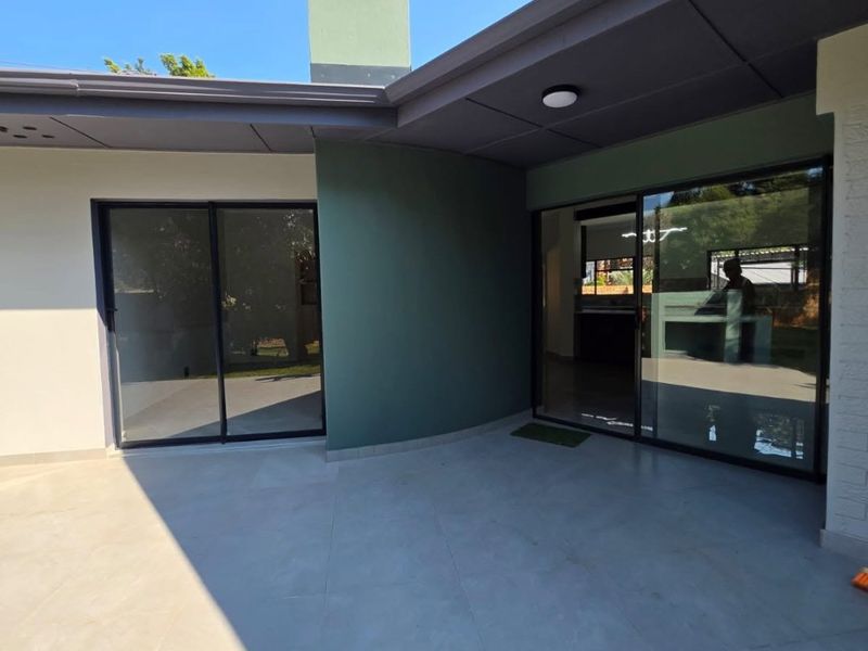A modern, covered patio area featuring large sliding glass doors, tiled flooring, and a prominent chimney, offering a clean and well-maintained outdoor living space.