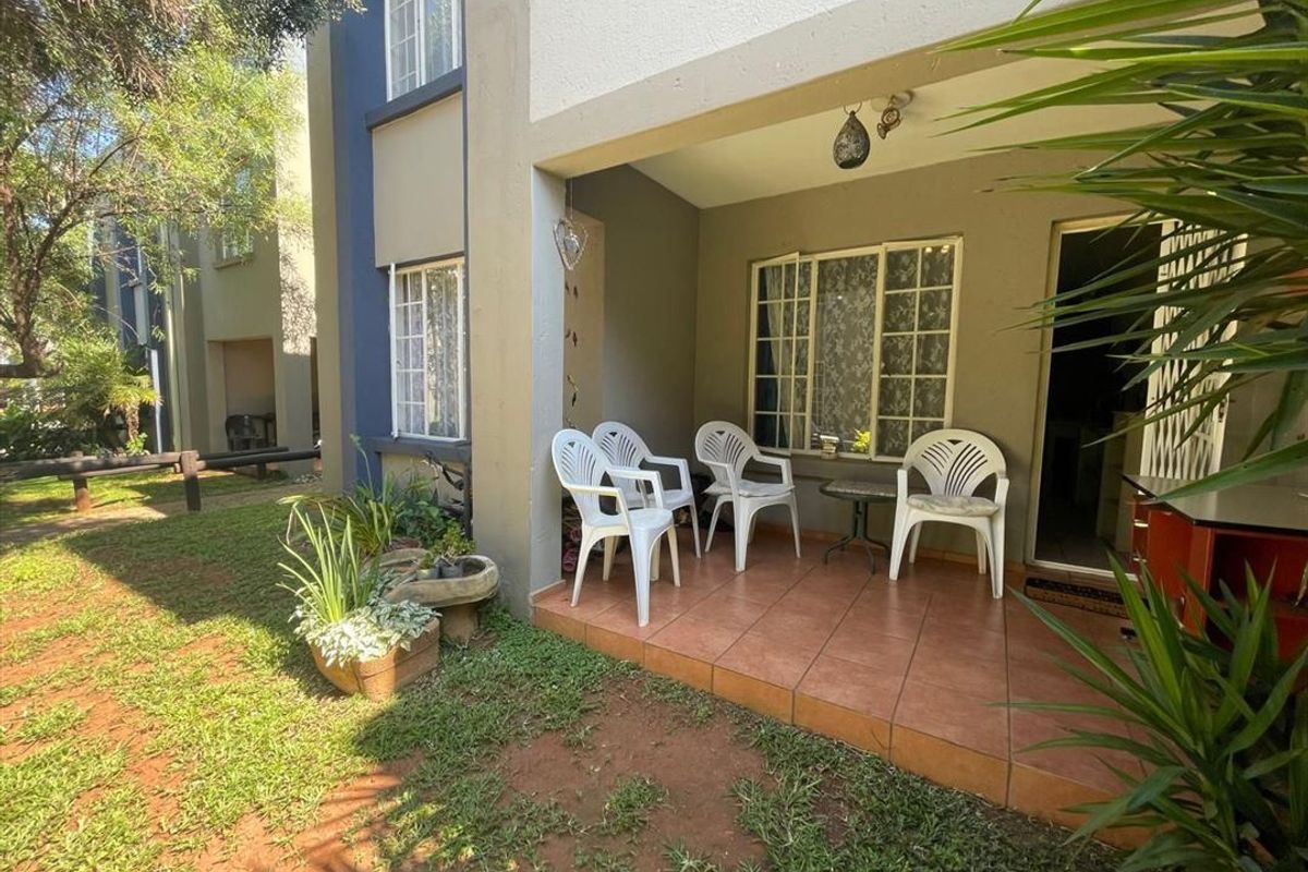 A covered ground-floor patio featuring tiled flooring and direct access to the garden area, providing a functional outdoor space for relaxation.