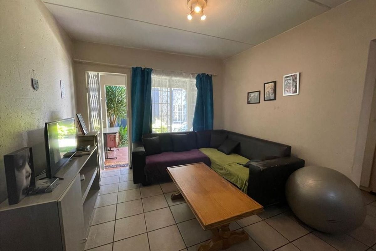 A living room featuring ceramic floor tiles and direct access to an outdoor area through a security gate.