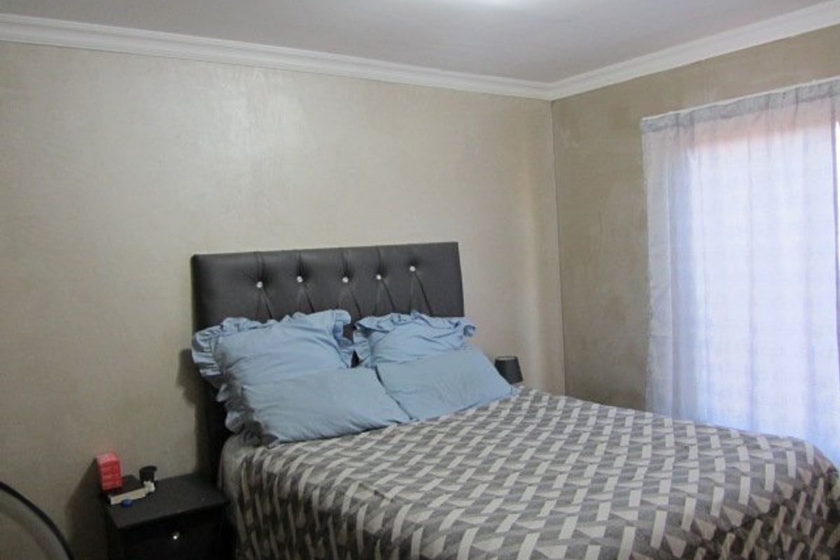 A standard bedroom featuring neutral wall finishes, crown molding, and a window with installed curtain rails.