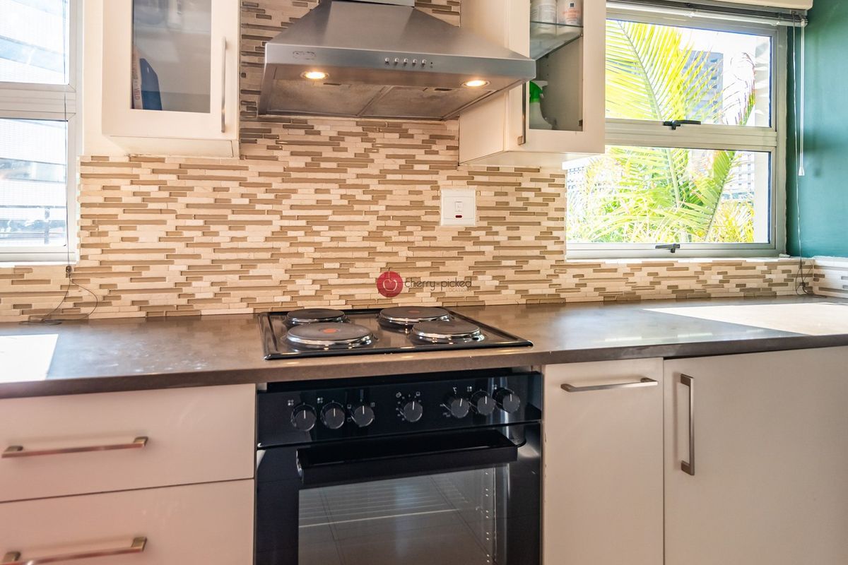 A functional kitchen featuring a built-in oven, electric hob, extractor fan, tiled backsplash, and ample cabinetry with laminate countertops.