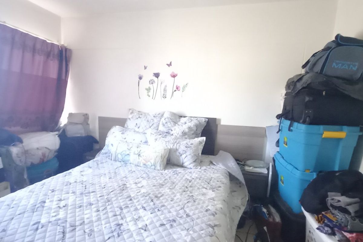 A bedroom featuring a built-in headboard and tiled flooring, currently used as a sleeping area.