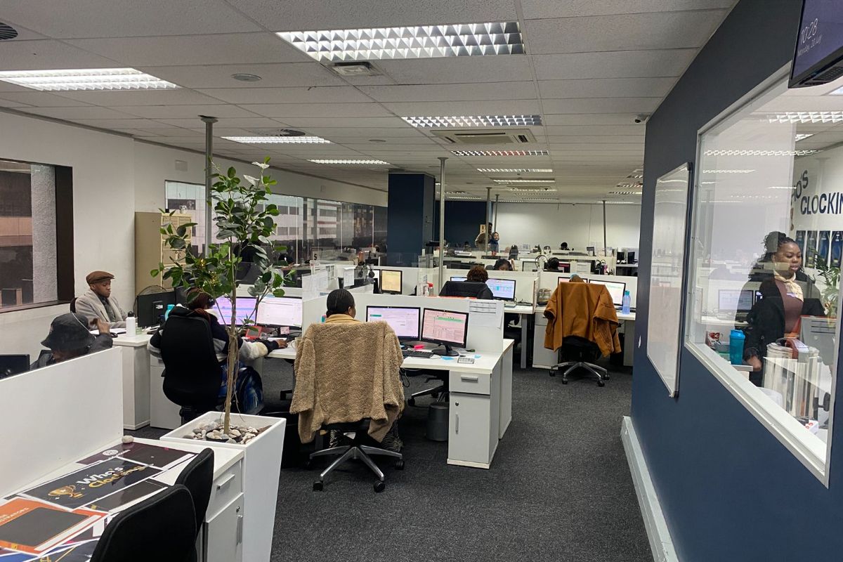 Open-plan commercial office space featuring carpeted flooring, suspended ceilings with recessed lighting, and integrated glass partitioning.