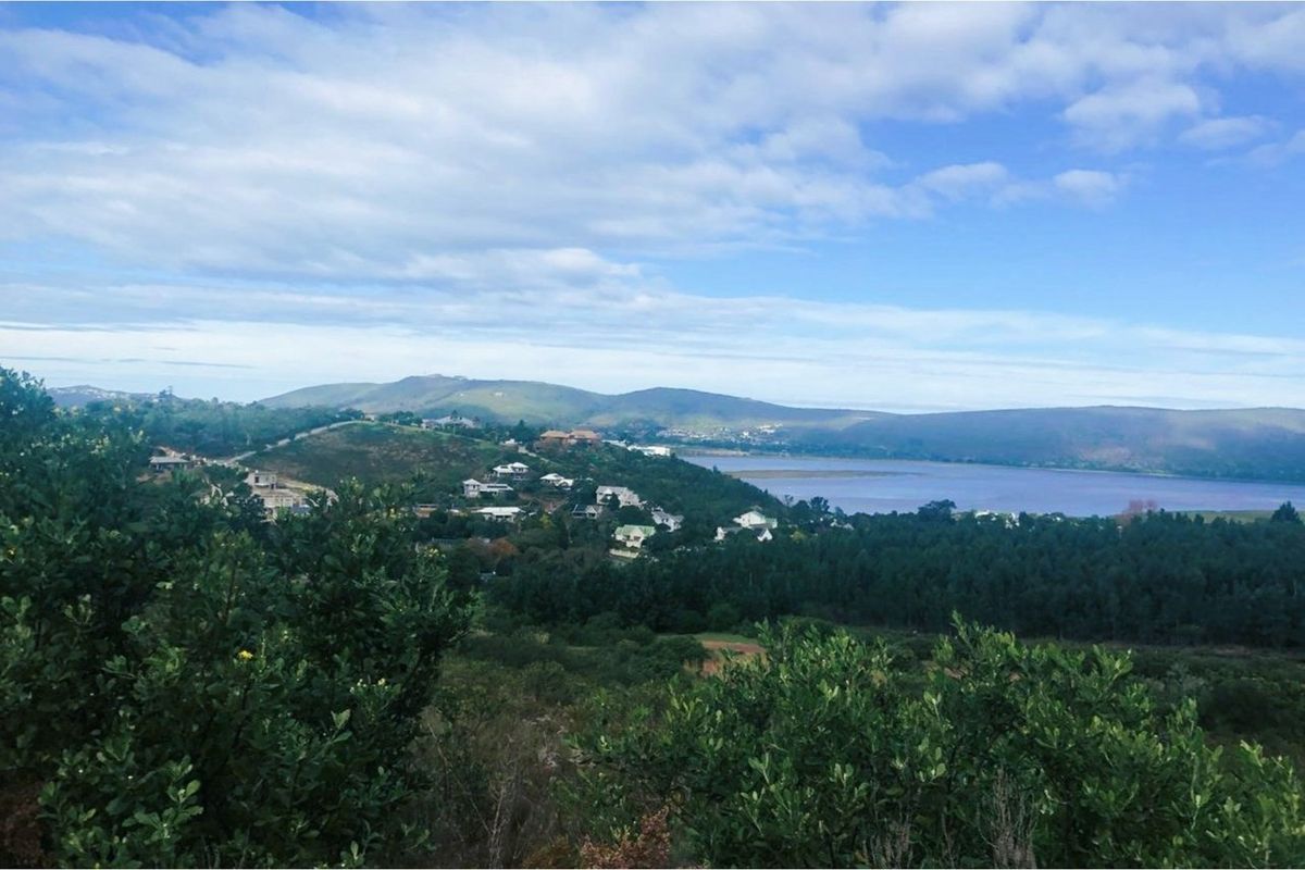 A scenic elevated view overlooking a landscape featuring rolling hills, a lake, and distant residential properties.