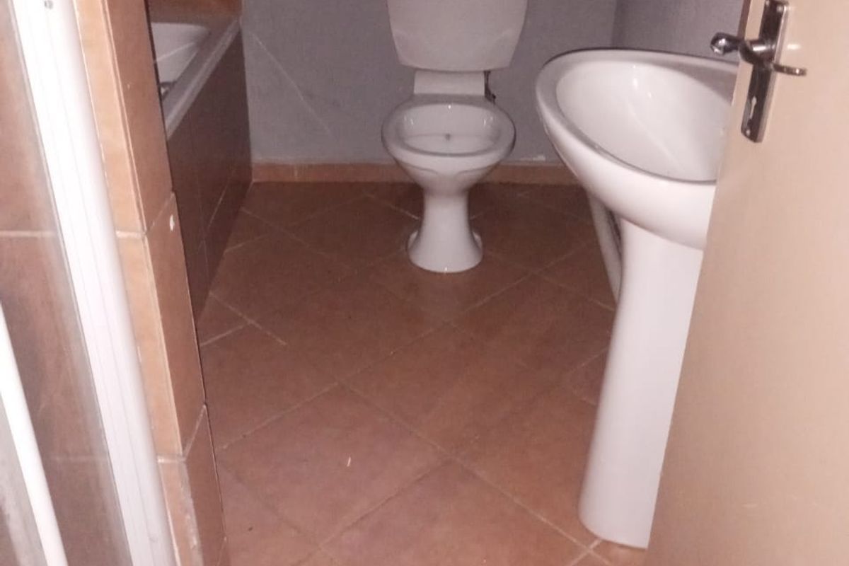A functional bathroom featuring a pedestal basin, toilet, bathtub, and shower enclosure with tiled flooring and walls.