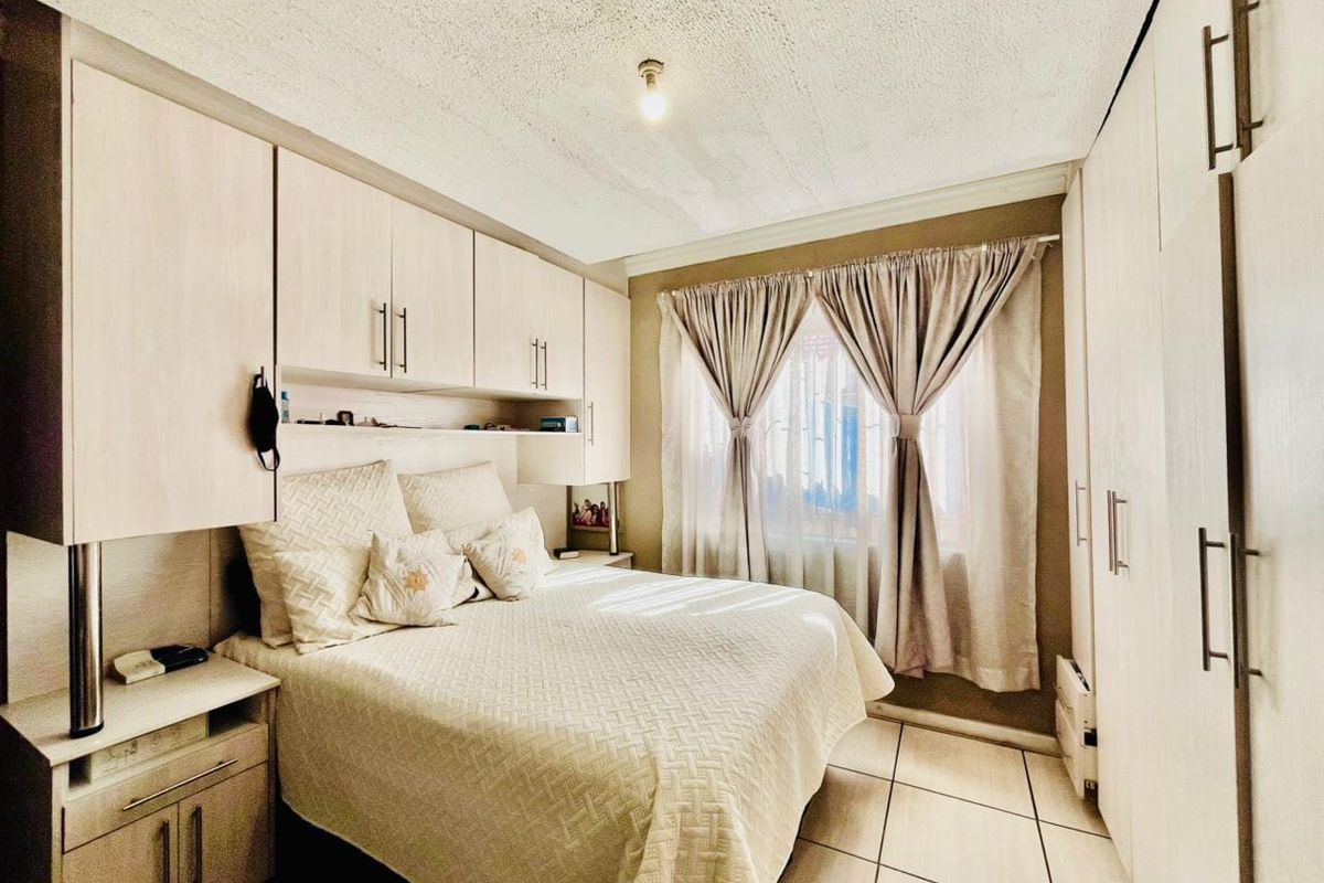 A bedroom featuring extensive built-in cabinetry, tiled flooring, and window security bars, offering functional storage and a neutral layout.