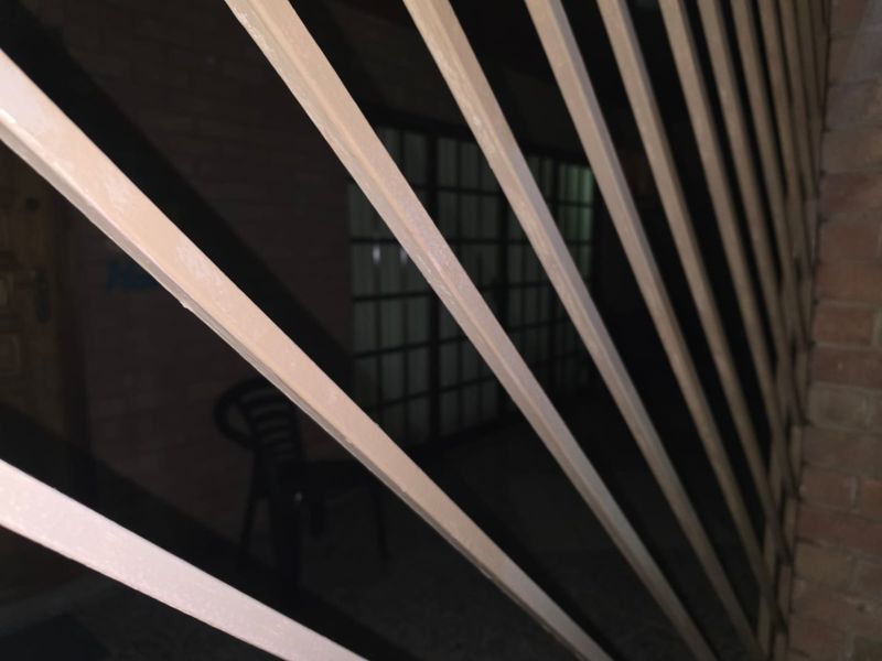 A low-light view of a building exterior partially obscured by a metal security gate.