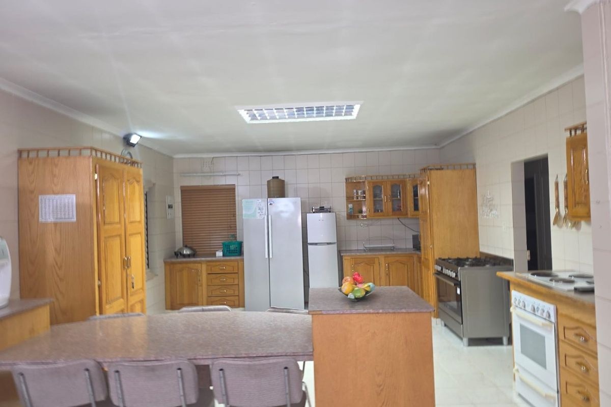 Spacious kitchen featuring extensive wooden cabinetry, tiled splashbacks, and a functional layout with a central island and integrated cooking appliances.