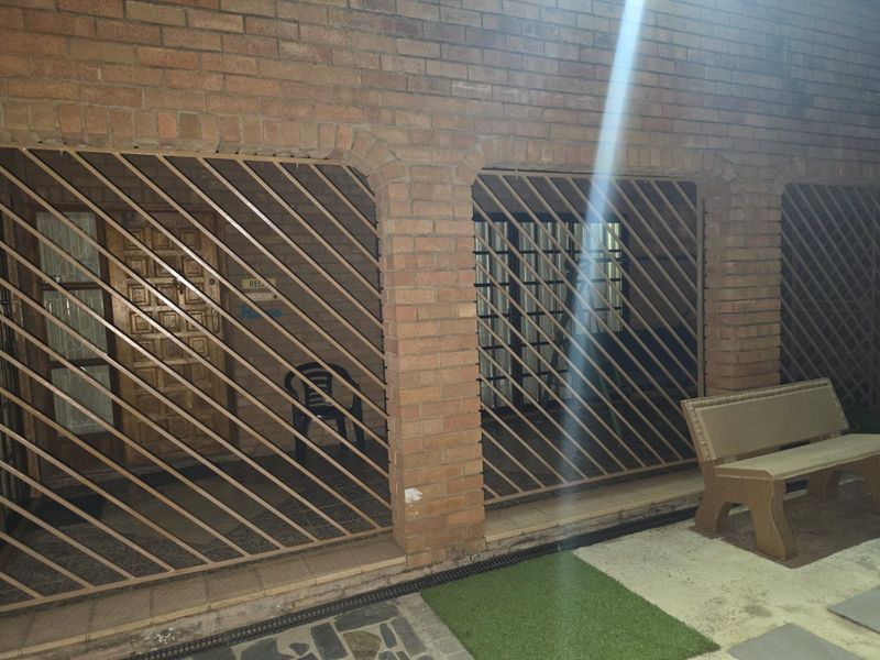 A covered patio area featuring exposed brick walls, security bars, and tiled flooring, providing a secure outdoor space.