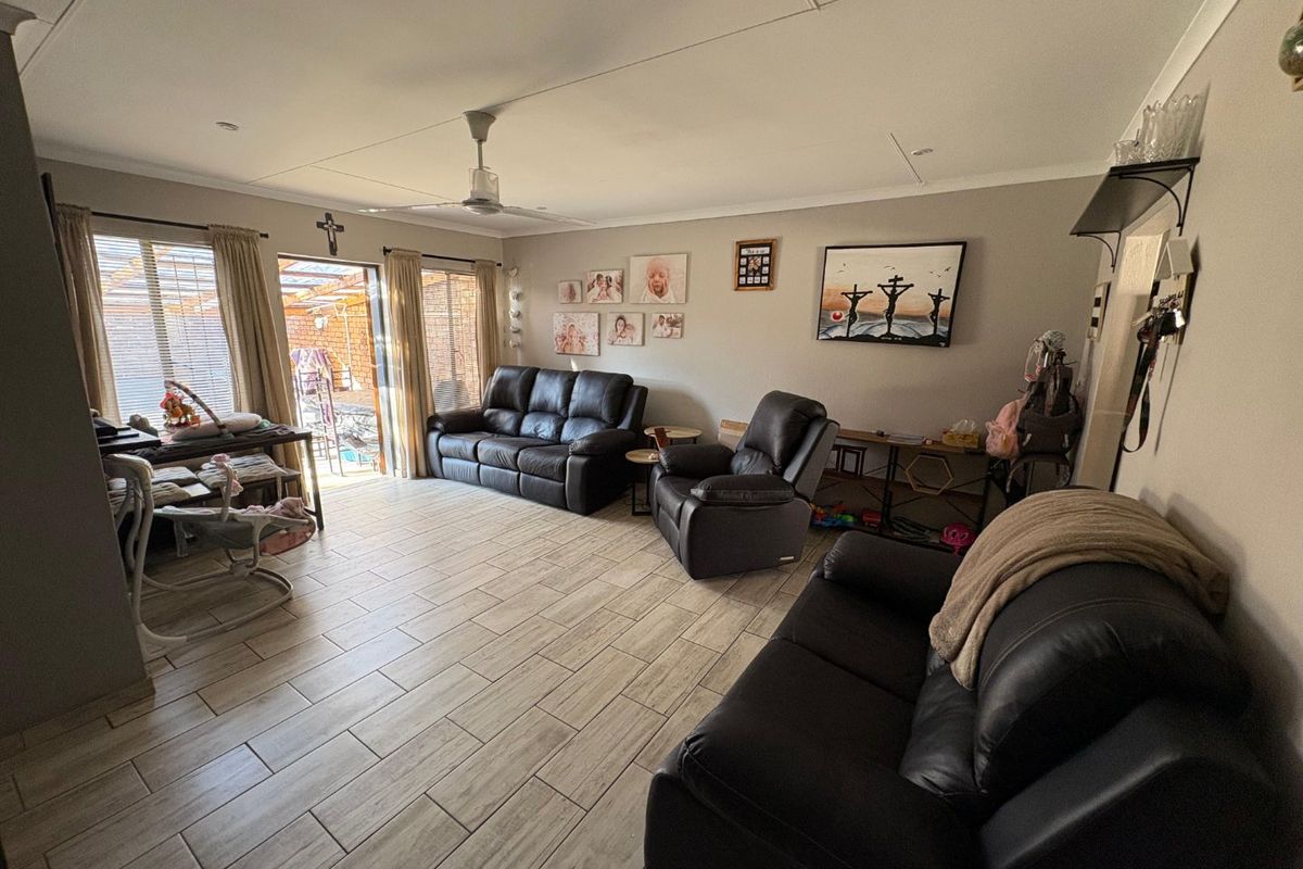 Spacious living room featuring neutral tiled flooring, a ceiling fan, and sliding glass doors providing access to the outdoor patio area.