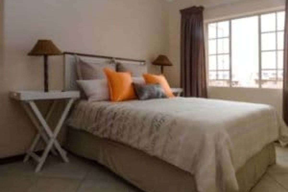 A bedroom featuring tiled flooring and a multi-pane window, providing a functional and neutral space.