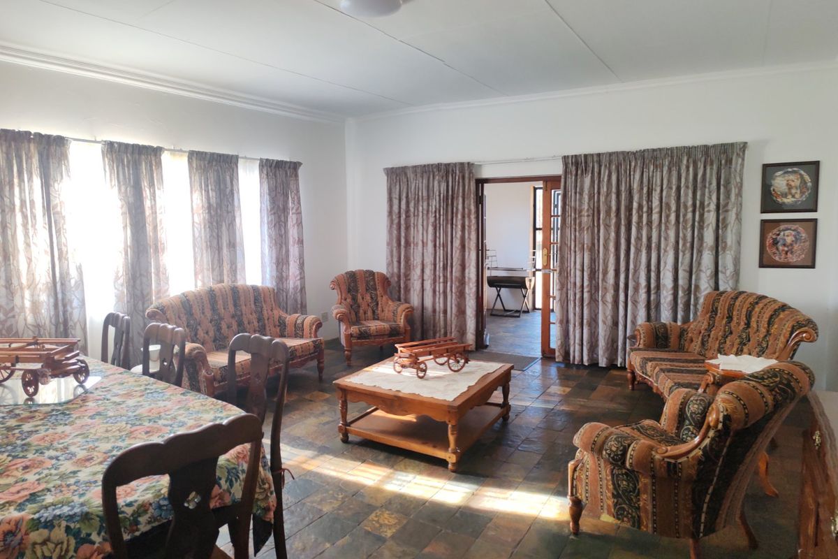 Spacious living and dining area featuring traditional slate tile flooring and direct access to an adjoining room through a sliding glass door.