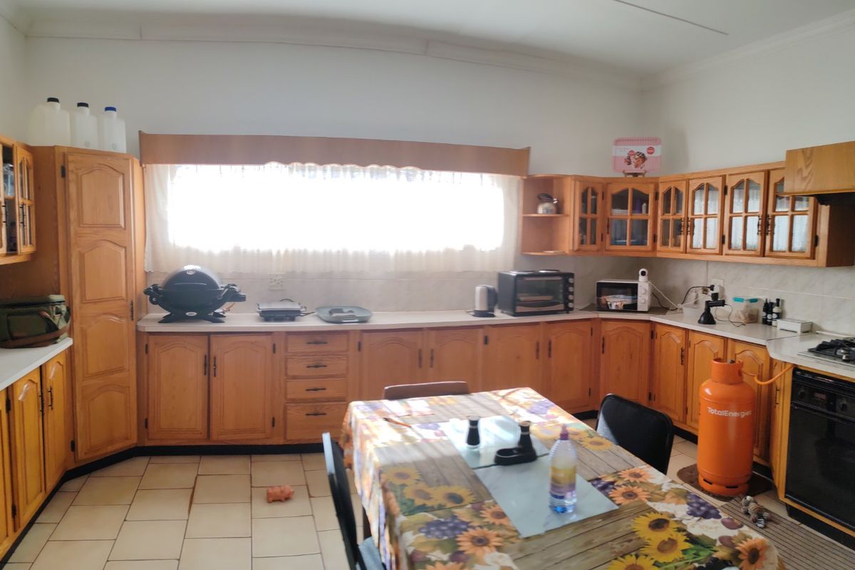 Spacious kitchen featuring extensive wooden cabinetry, gas hob, built-in oven, and tiled flooring, offering a functional layout with ample storage space.