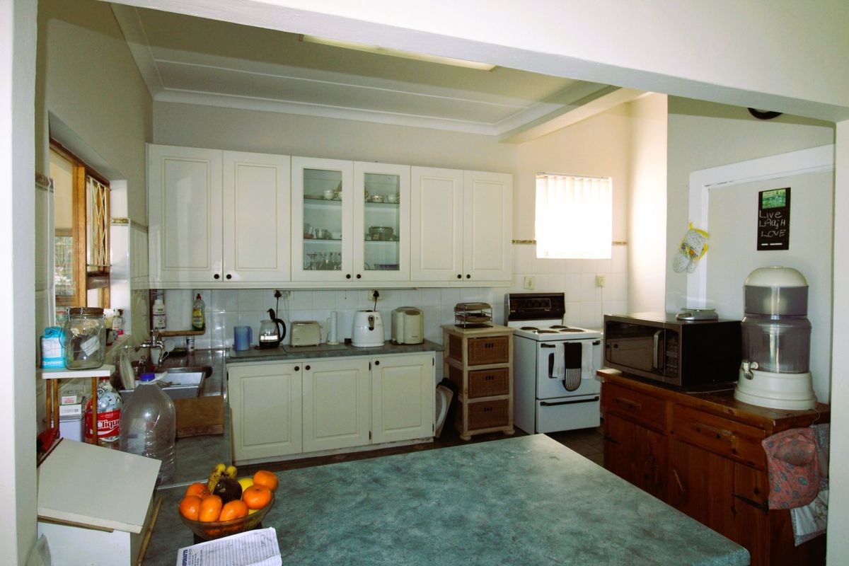 A functional kitchen featuring white cabinetry, tiled backsplash, laminate countertops, and a freestanding stove, offering a classic layout with potential for modernization.