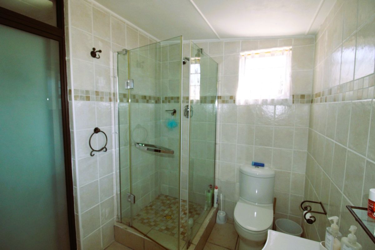 A functional bathroom featuring a glass-enclosed shower, tiled walls, and standard sanitary fixtures.