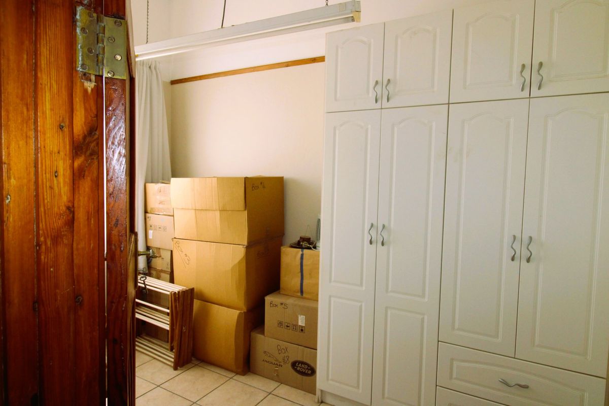 Bedroom featuring white built-in cupboards and tiled flooring, currently used for storage.