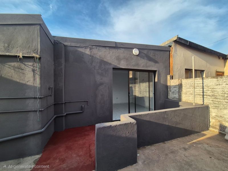 Rear exterior view of the property featuring a sliding glass door, painted concrete patio area, and exposed exterior plumbing.