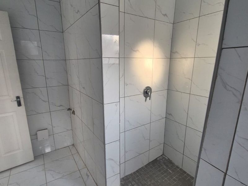 A modern bathroom featuring a walk-in shower with rainfall shower head and marble-look ceramic tiling throughout.