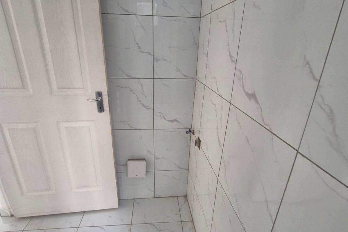 An unfinished bathroom space featuring marble-look ceramic wall and floor tiles, currently awaiting the installation of plumbing fixtures and sanitary ware.