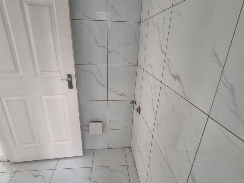 An unfinished bathroom space featuring marble-look ceramic wall and floor tiles, currently awaiting the installation of plumbing fixtures and sanitary ware.