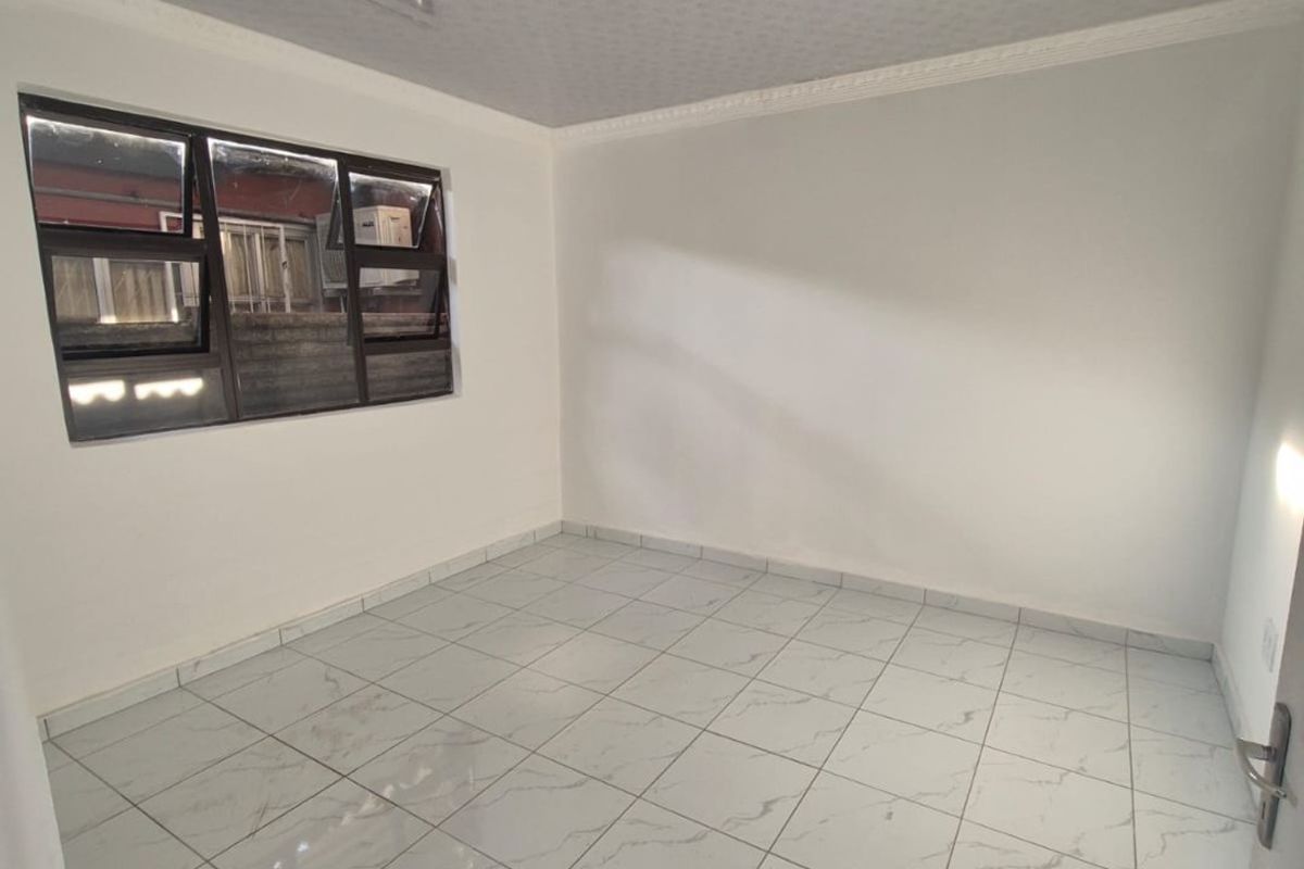 A clean, empty bedroom featuring modern white marble-look floor tiles and aluminium window frames, ready for personalization.