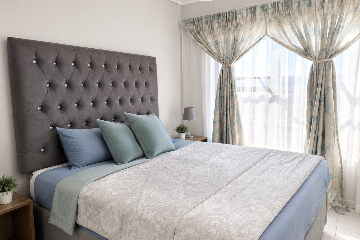 A well-maintained bedroom featuring neutral wall finishes, tiled flooring, and large windows with installed curtain tracks, providing ample natural light.