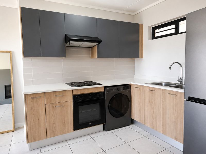 Modern kitchen featuring two-tone cabinetry, integrated oven and hob, tiled backsplash, and sleek countertops in a clean, well-maintained space.